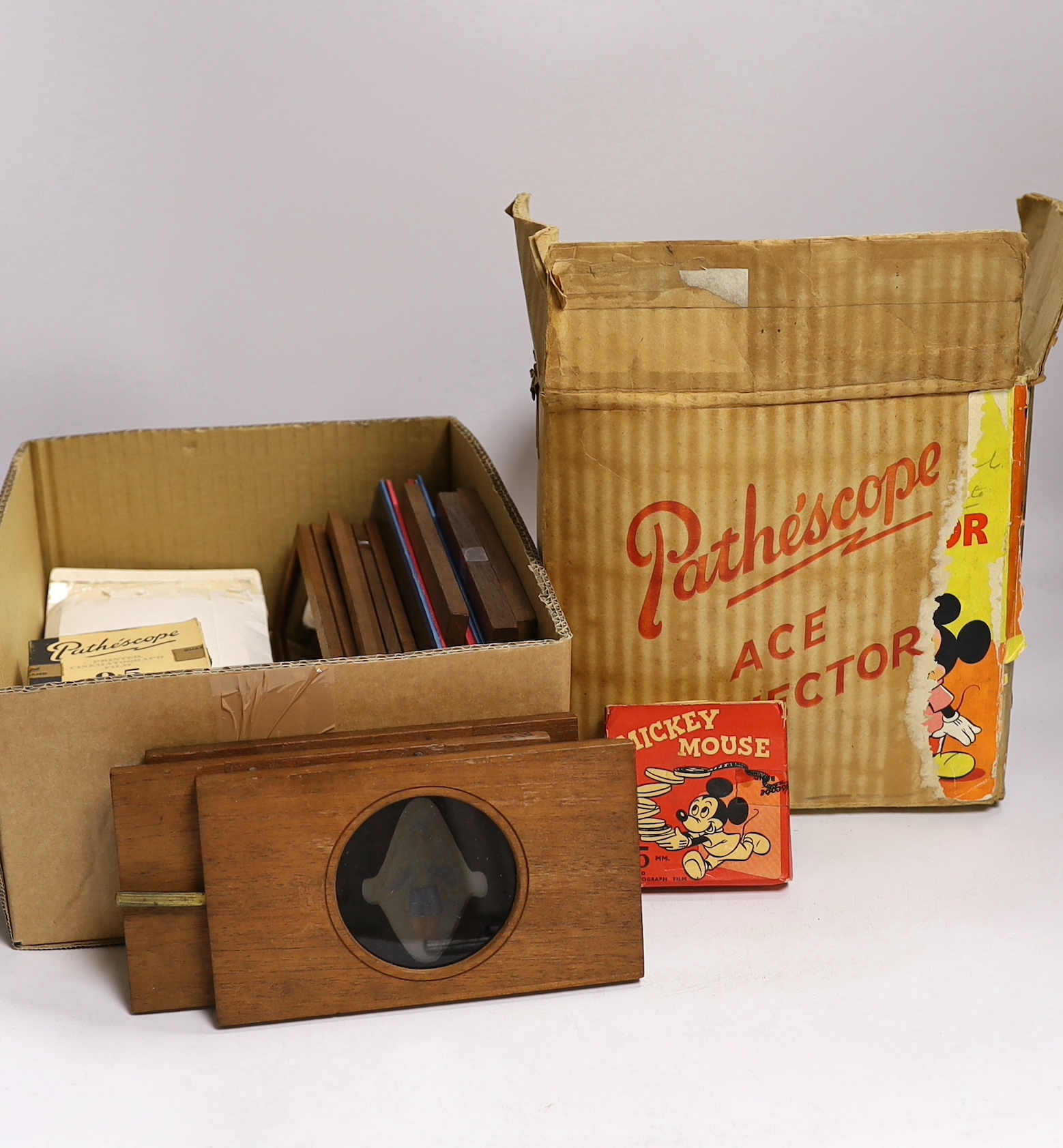 A collection of magic lantern slides, including some painted examples and some in frames, together with a 9.5mm Pathescope Ace Projector with five reels including a Disney Mickey Mouse reel, plus a few early 20th century